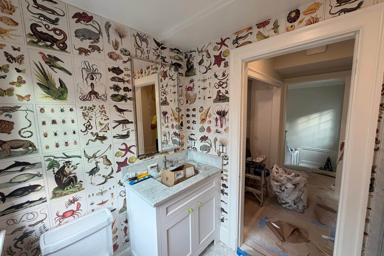 The same bathroom from the door, paper running over the doorway, with the hallway still under protection paper