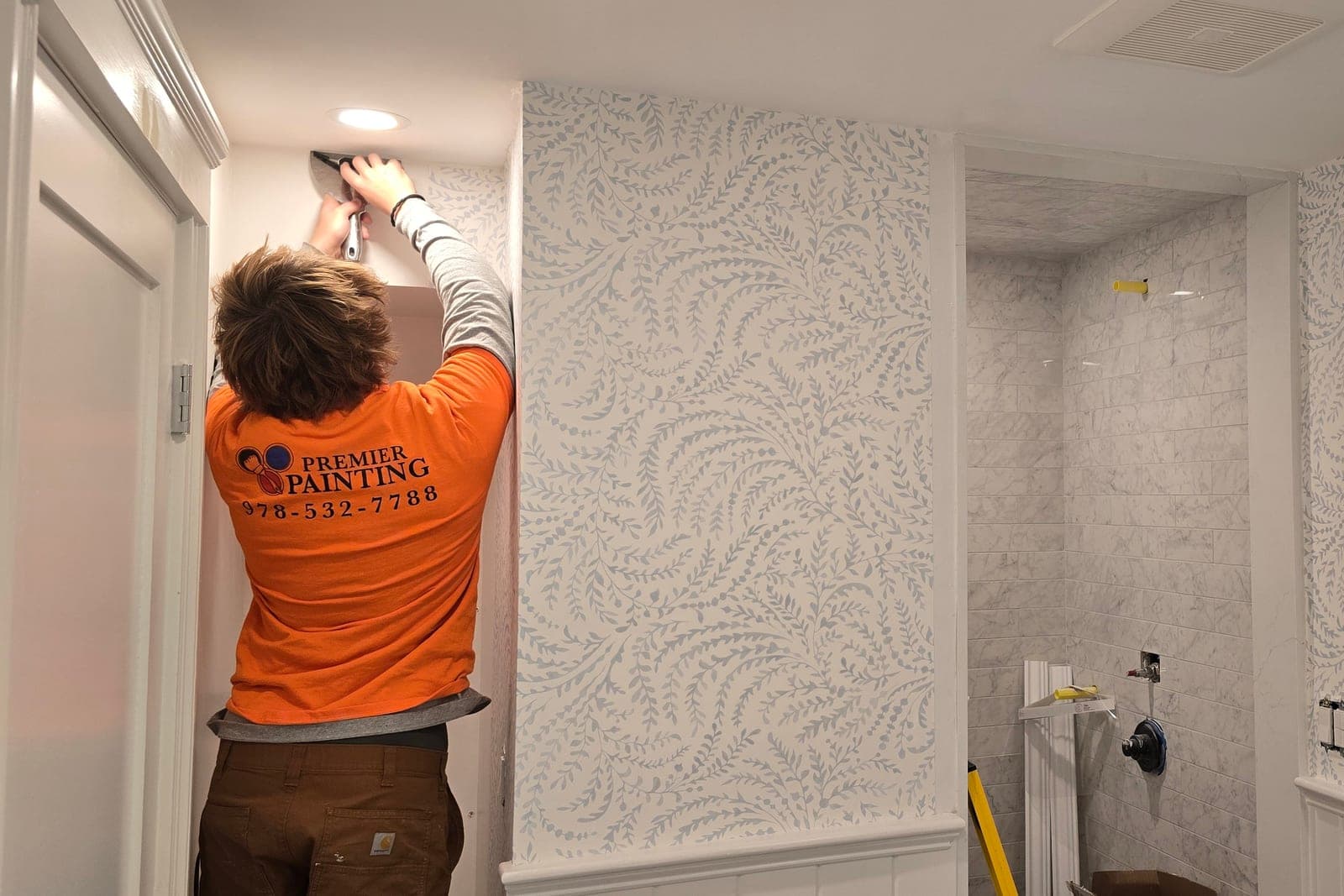 Installer working a grey damask paper into a corner