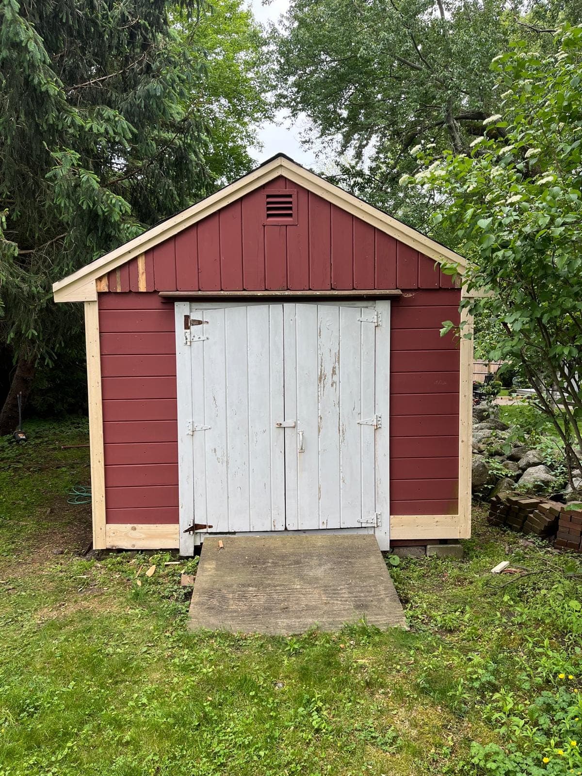 Double doors of a red shed framed in new pine casing and corner boards
