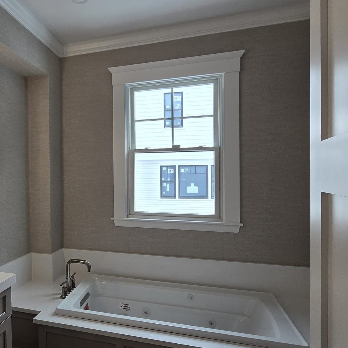 Grey grasscloth wrapping the window wall above a soaking tub