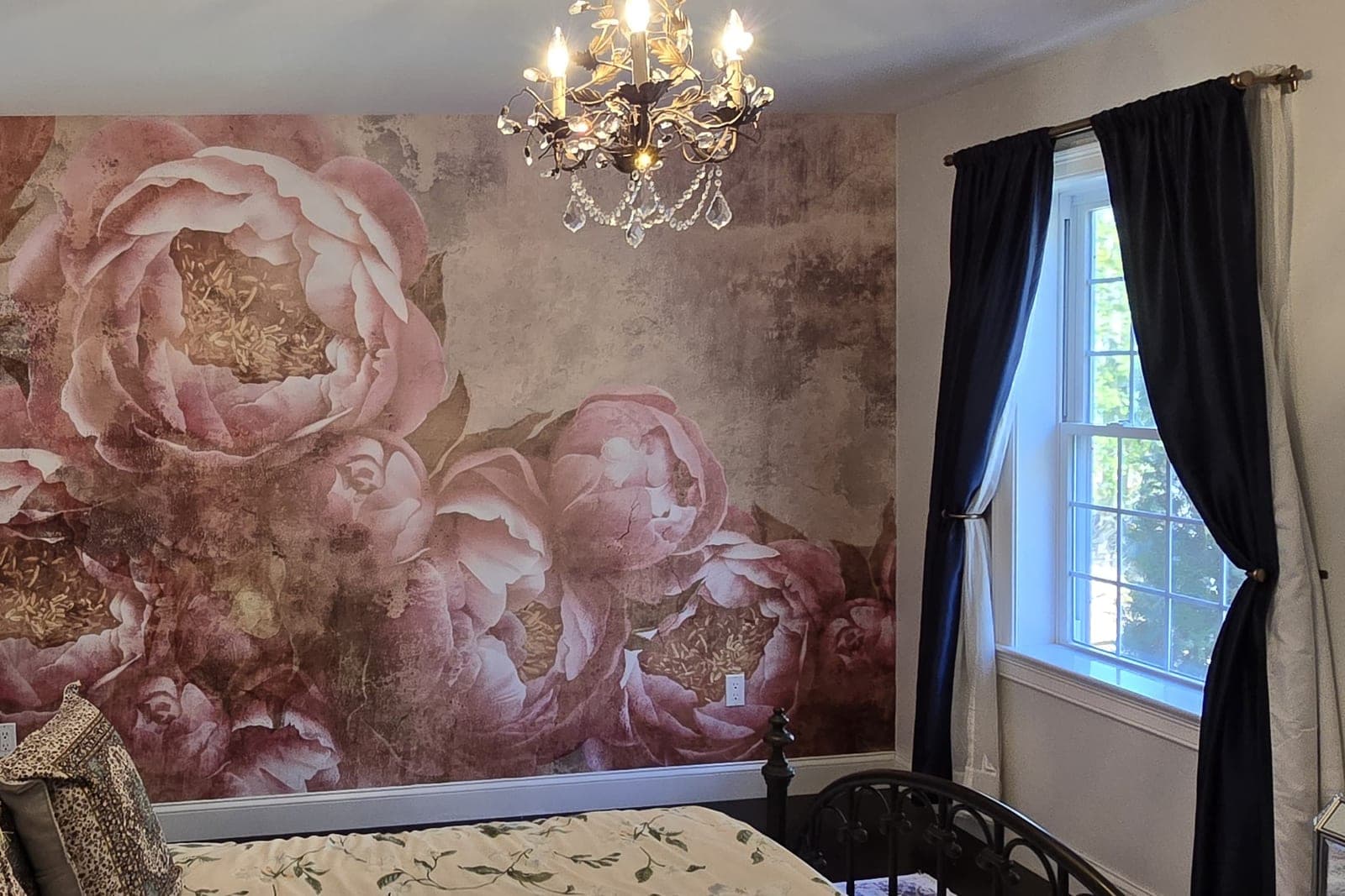 Bedroom with a large-scale peony mural in blush and rose behind the bed, under a crystal chandelier