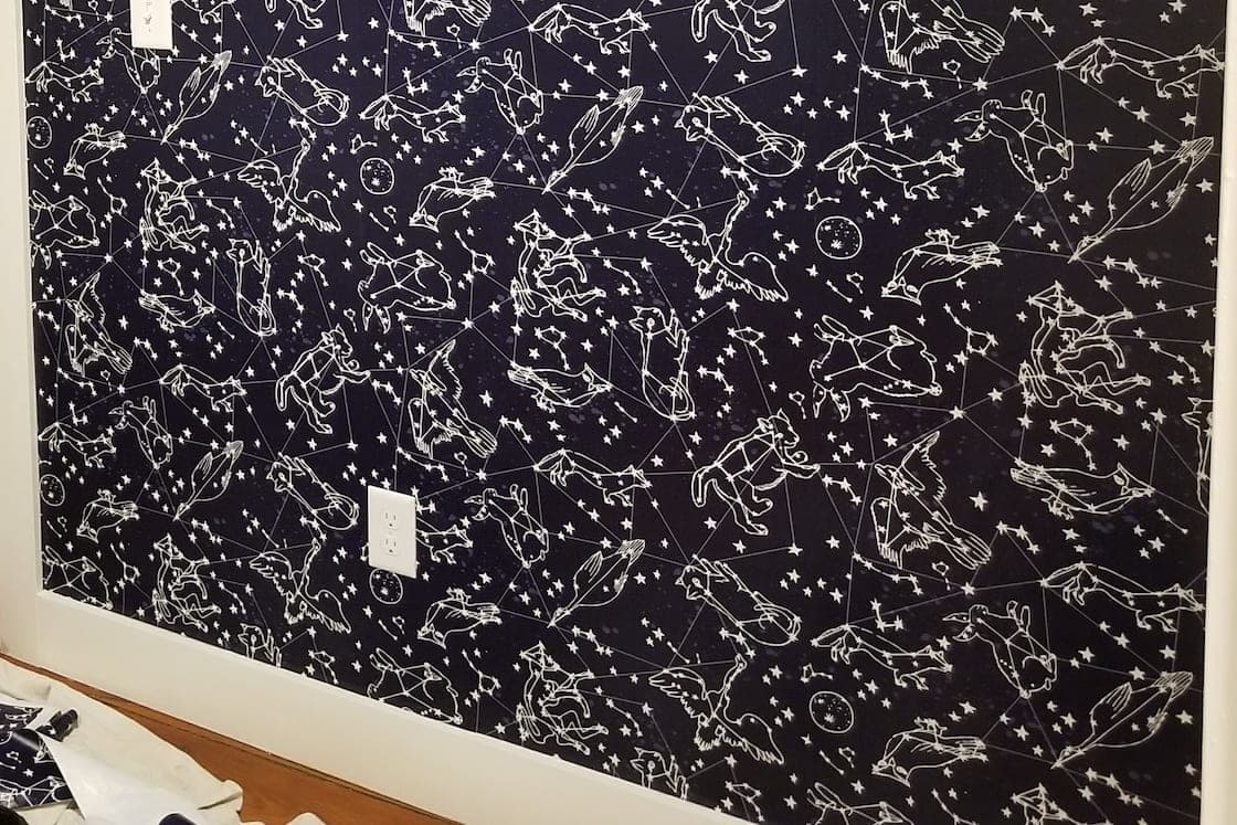 Accent wall in a navy constellation print with white line-drawn figures and stars